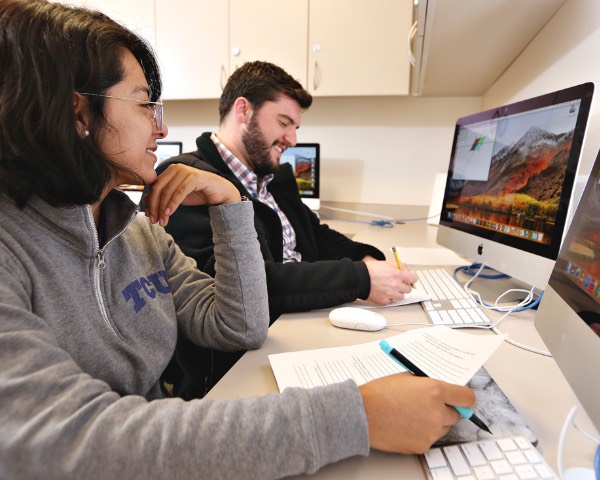Students discuss details of a curriculum plan while working at computer workstations