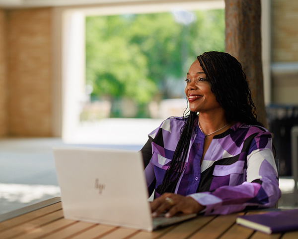 Woman works on laptop while seated at a café table