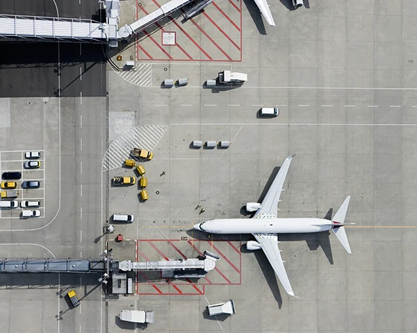 Aerial view of a commercial aircraft, surrounded by ground support vehicles, at an airport terminal