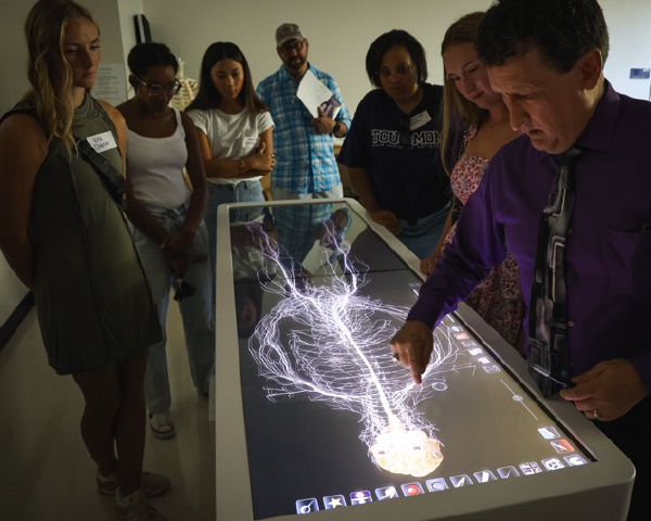 Students observing a medical digital display with Dr. Justiss