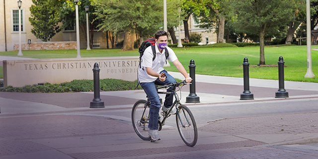 TCU student cycling while wearing a face covering