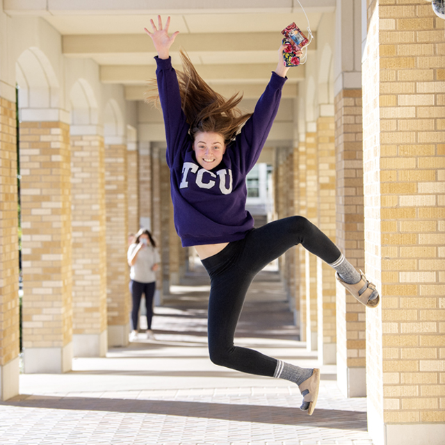 TCU student jumps for joy in the Commons