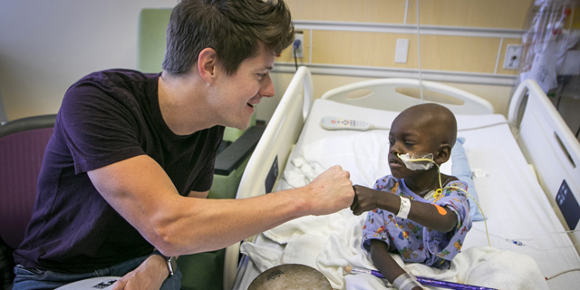 TCU alum and physician J. Mack Slaughter does music therapy with a young patient.