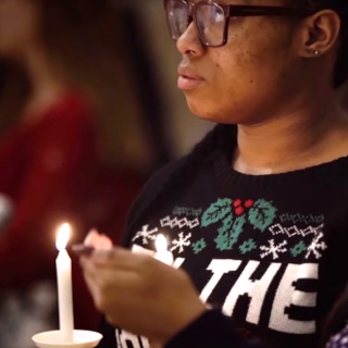 Illuminated by handheld candles, two female TCU students listen to a Christmas service in the TCU Chapel.