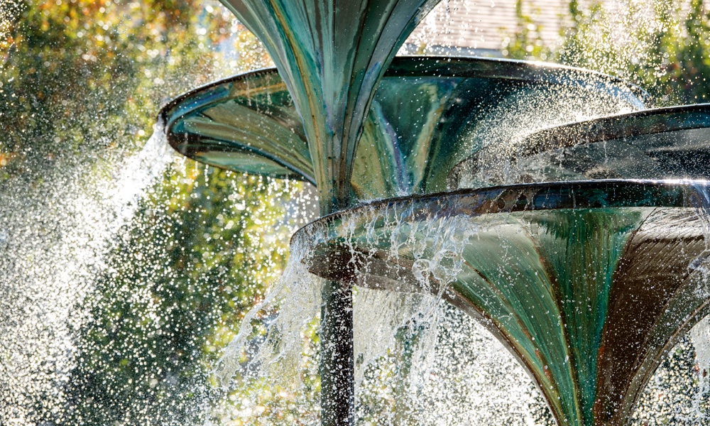 Close up view of water cascading from the trumpet-shaped forms of TCU landmark Frog Fountain