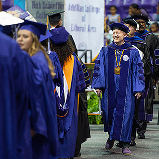 Chancellor Victor J. Boschini, Jr., in full academic regalia, leading a commencement processional of faculty