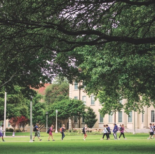 Students seen from a distance walking across campus near TCU's main administration building