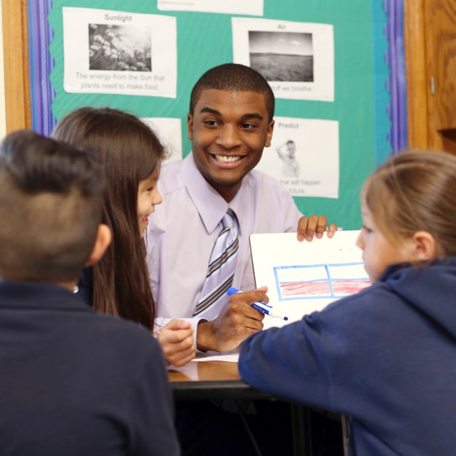 Male teacher discusses a chart with four young students