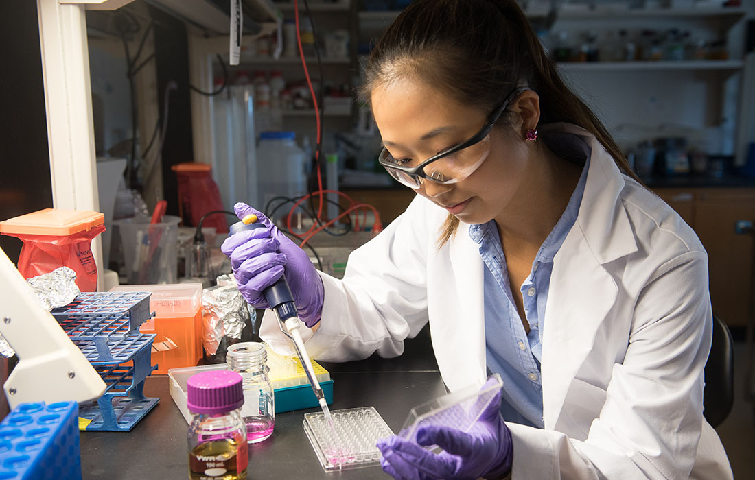 A biology student carefully places samples into a tray