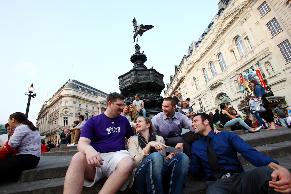 A small group of TCU students gather in front of an ornate fountain in a piazza.