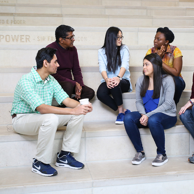 students sit on the library steps surrounded by different languages