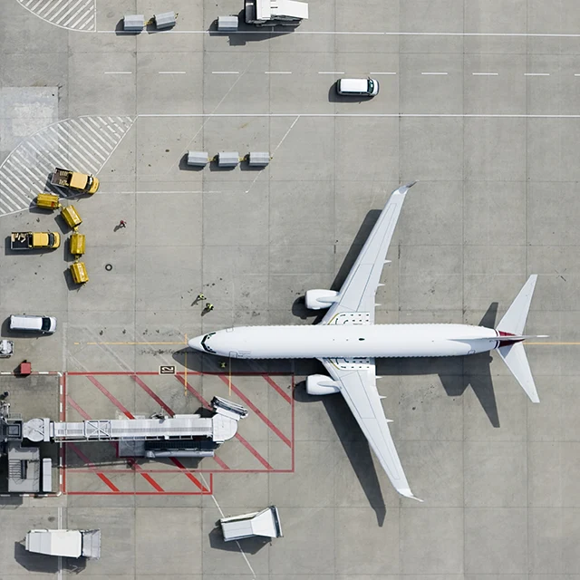 Aerial view of a commercial aircraft, surrounded by support vehicles
