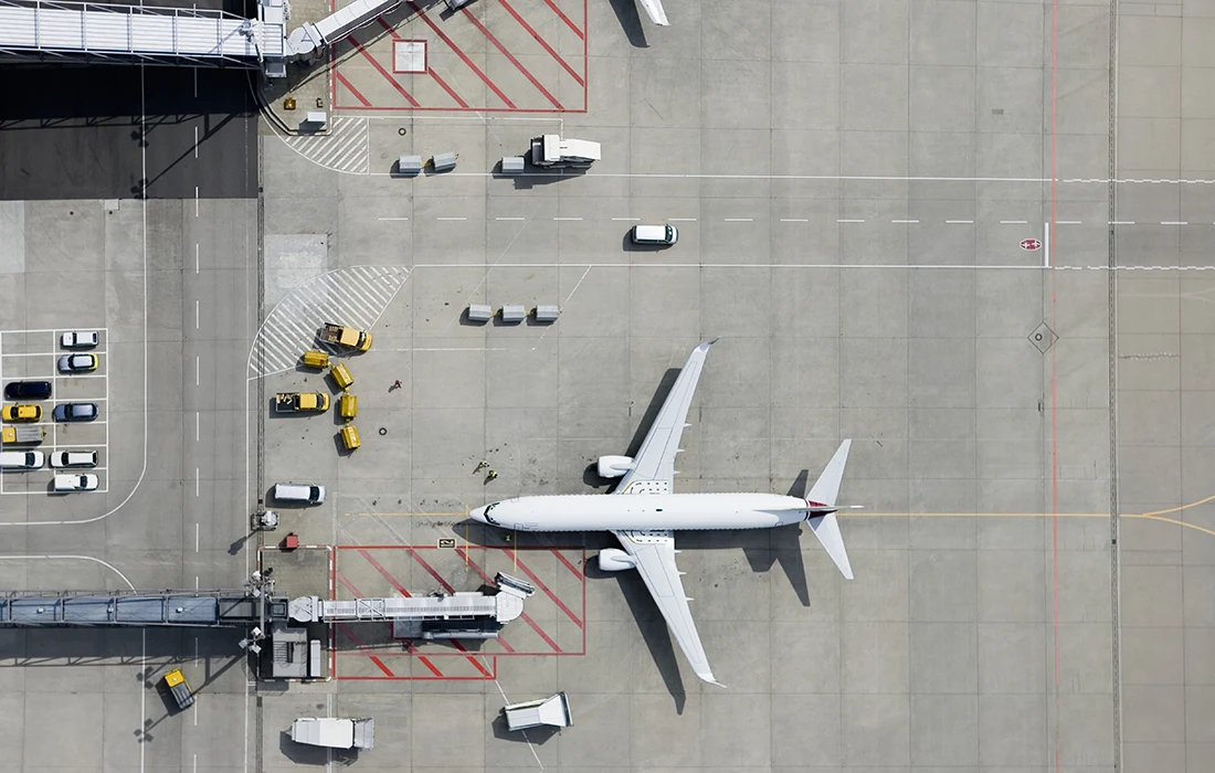 Aerial view of a commercial aircraft, surrounded by support vehicles