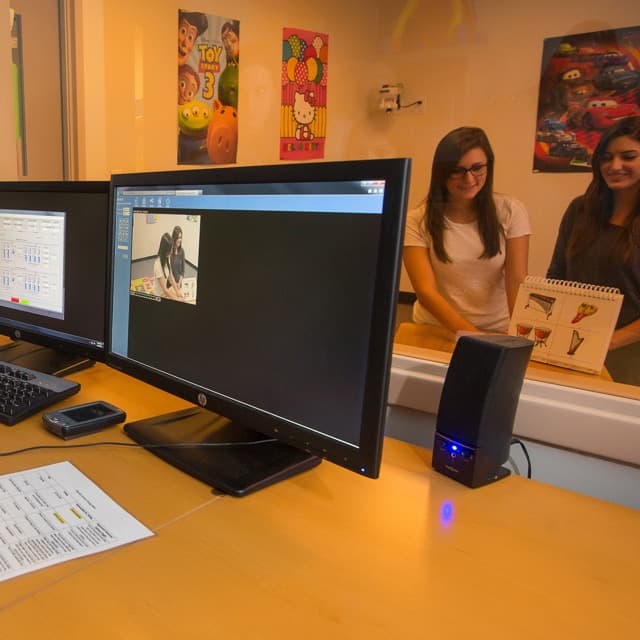 Students conduct a behavioral study of two female subjects from behind a two-way mirror