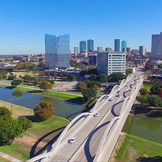 A view of the Seventh Street bridge leading into downtown Fort Worth, Texas, against a cloudless blue sky 