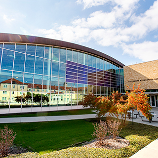 An exterior of the TCU Campus Rec center; other campus buildings are reflected in its shiny surface.