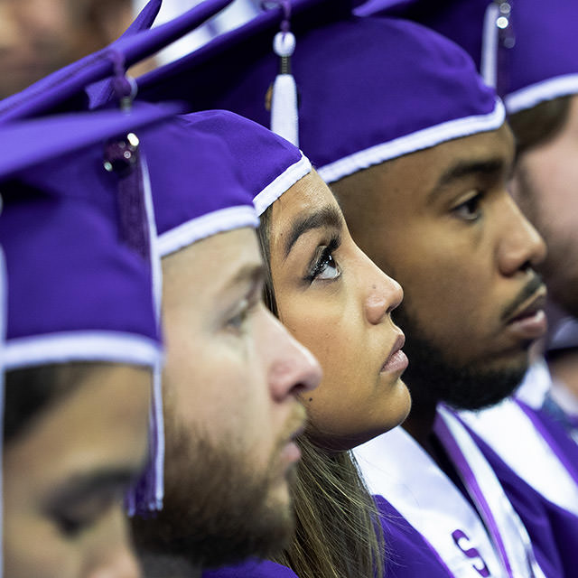 TCU students in regalia, seated at commencement