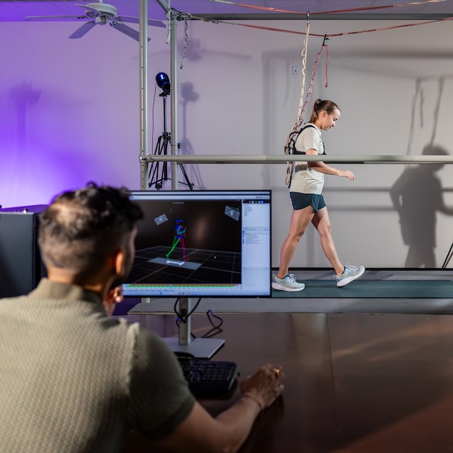 Researcher with screen watches athlete on treadmill