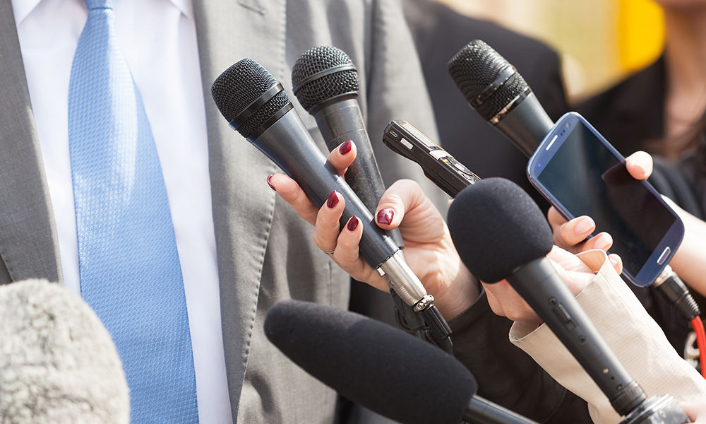 many hands holding a variety of microphones