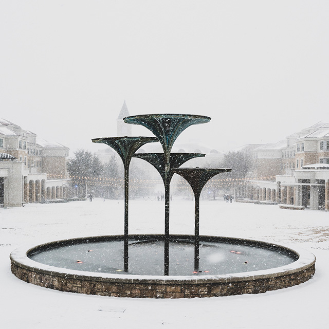 A frosty Frog Fountain, with a snow-covered Campus Commons in the background