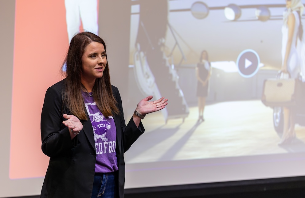 Ackerman speaks in front of a screen