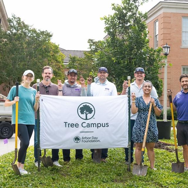 Tree-planters hold Arbor Day Sign
