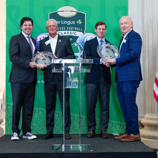 Four men stand on a stage holding crystal plates.