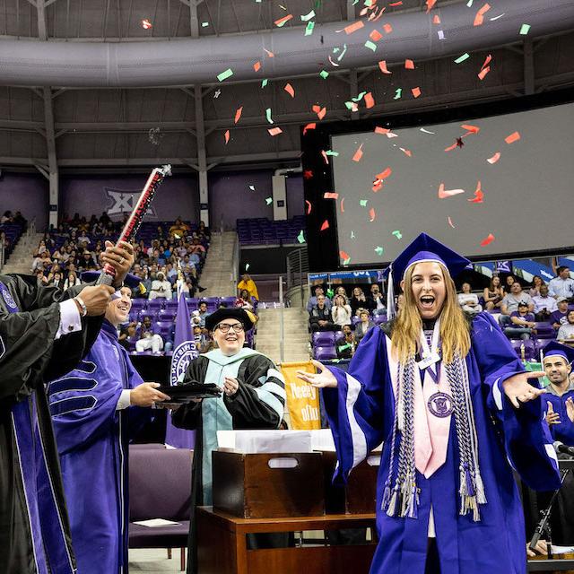 Trustees pop confetti as the 100,000th living alum walks across the stage at commencement