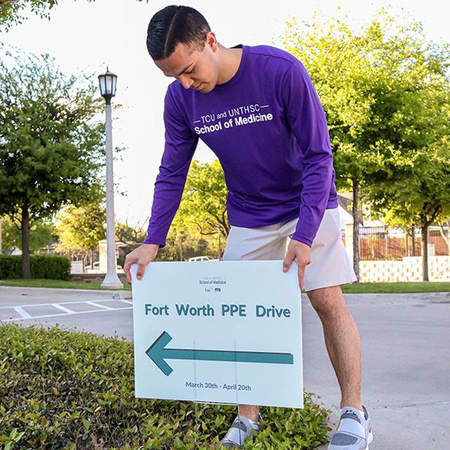 Photo of student placing sign for PPE drive