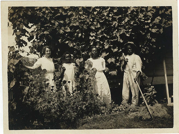 One white person and 3 Black people pose in front of a tree