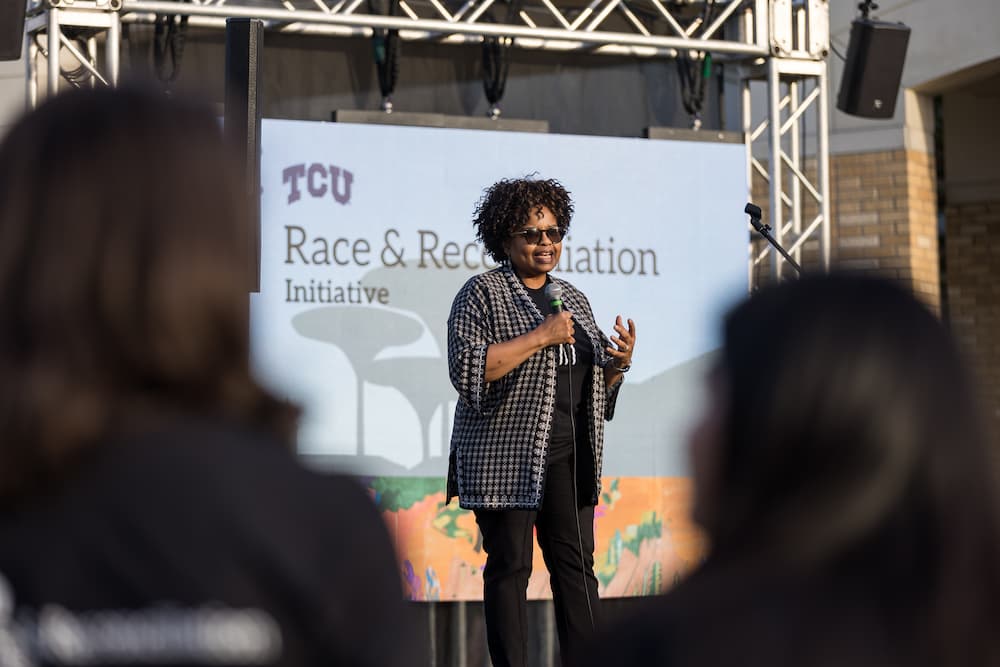 Dr. Amiso George speaks on stage to a crowd