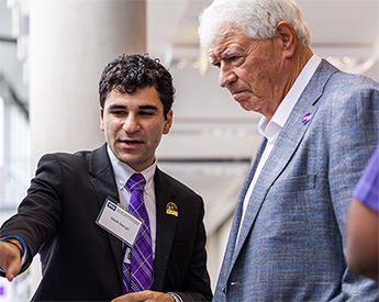 Two men in suits converse at an event